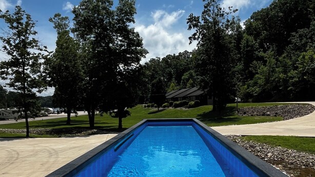 En rektangulær swimmingpool med en træterrasse foran.