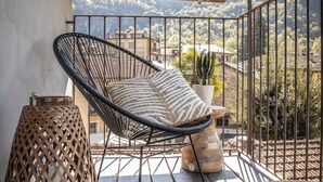 A wooden balcony with a wicker chair and a woven stool, overlooking a mountainous landscape. - Stella - panoramic attic in the BOTTONERA casa vacanza in alpine design (Chiavenna)
