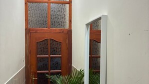 Un estrecho pasillo con una puerta de madera que tiene paneles de vidrio.