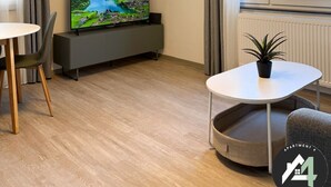 Un salon moderne avec un téléviseur à écran plat, une table à manger et une plante en pot.