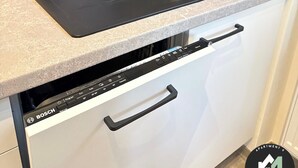 Une cuisine avec un évier noir, un distributeur de savon et un lave-vaisselle Bosch.