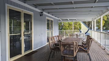A covered patio with a table and chairs, a sliding glass door, and a railing.