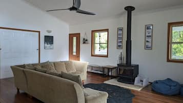 A living room with a sofa, a table, a fireplace, and a ceiling fan.