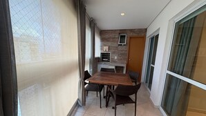 A narrow balcony with a dining table and chairs, a sliding glass door, and a small kitchenette area. - Enjoy a Convenient Location and Comfort in Jardim Goias - Mfes (Goiânia)