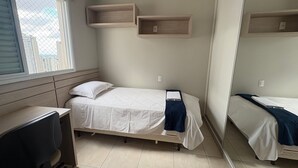 A small, tidy room with a single bed, a desk, and two wall-mounted shelves. - Enjoy a Convenient Location and Comfort in Jardim Goias - Mfes (Goiânia)