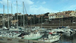 A marina with multiple boats docked, surrounded by hillside buildings. - Exclusive Villa on the Pelosa Beach (Stintino)