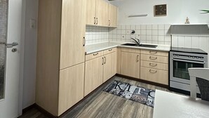 A compact kitchen with wooden cabinets, a built-in oven, and a tiled backsplash. - Holiday Oasis 2.0 near Legoland Günzburg (Günzburg)