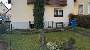A two-story house with a sloped roof, a small balcony, and a tall coniferous tree in the front yard. - Holiday Oasis 2.0 near Legoland Günzburg (Günzburg)