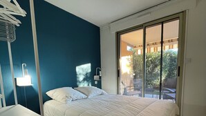 A bedroom with a bed, a desk, and a sliding glass door leading to a balcony. - Apartment Sea View Le Lavandou (Le Lavandou)