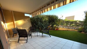 A patio with tiled flooring, outdoor furniture, and a well-maintained lawn. - Apartment Sea View Le Lavandou (Le Lavandou)