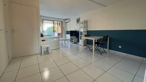 A spacious living area with a tiled floor, a dining table with chairs, a sofa, and a TV. - Apartment Sea View Le Lavandou (Le Lavandou)