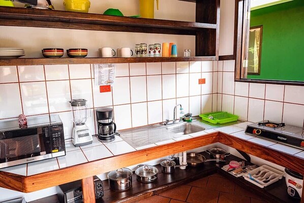 A kitchen with a microwave, coffee maker, sink, and various kitchen utensils. - Venus of the beach (Montezuma)