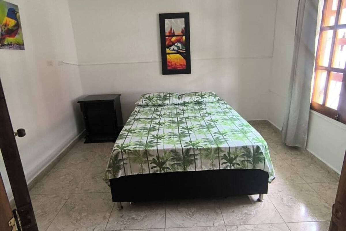 Une chambre à coucher avec un lit, un tableau au mur et une fenêtre.