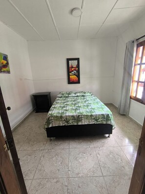 A bedroom with a bed, a picture on the wall, and a window. - Oliva's House (Jardín)