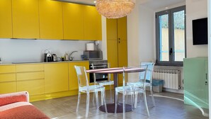 Una cocina moderna con gabinetes amarillos, un comedor con sillas transparentes y un ventanal grande.