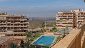 Un hotel con varios balcones, piscina y vista a un paisaje lejano.