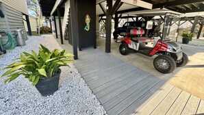 Un espacio al aire libre cubierto con un sendero pavimentado, un carrito de golf rojo y blanco, y una planta en maceta.