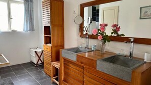 A bathroom with two sinks, a wooden vanity, a mirror, and a window with curtains. - Clos Beldane (Le Tâtre)