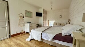 A bedroom with a bed, a dresser, a TV, and a dress form. - Clos Beldane (Le Tâtre)