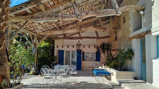 An outdoor patio area with a wooden pergola, a pool, and a dining table with chairs. - Clos Beldane (Le Tâtre)