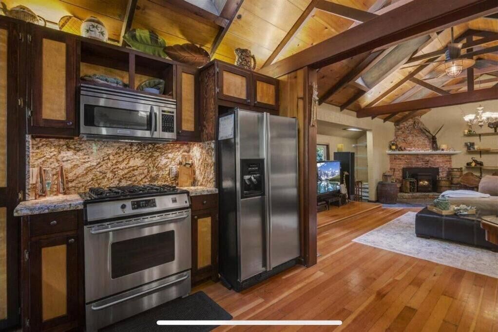 A kitchen with stainless steel appliances, wooden cabinets, and a stone backsplash.