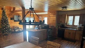 A cozy cabin-style kitchen with wooden floors, a dining area, and a Christmas tree. - Mountain feel/10 minutes from the city! (Pittsburgh)