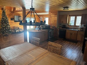 Una cocina acogedora estilo cabaña, con pisos de madera, zona de comedor y un árbol de Navidad.