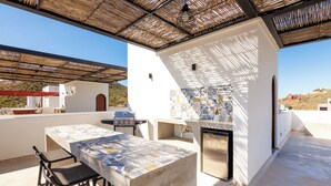 An outdoor patio with a table and chairs, a grill, and a tiled backsplash. - Luxury Home in Brand New Complex in Cerritos Beach (El Pescadero)