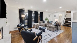 Ein modernes Wohnzimmer mit einem Ecksofa, einem Kamin und einer Treppe, die zu einer oberen Etage führt.