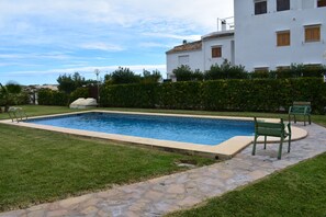 A rectangular swimming pool with a stone border, surrounded by a well-maintained lawn and a hedge. - At711 in Oliva With 2 Bedrooms and 1 Bathrooms (Oliva)