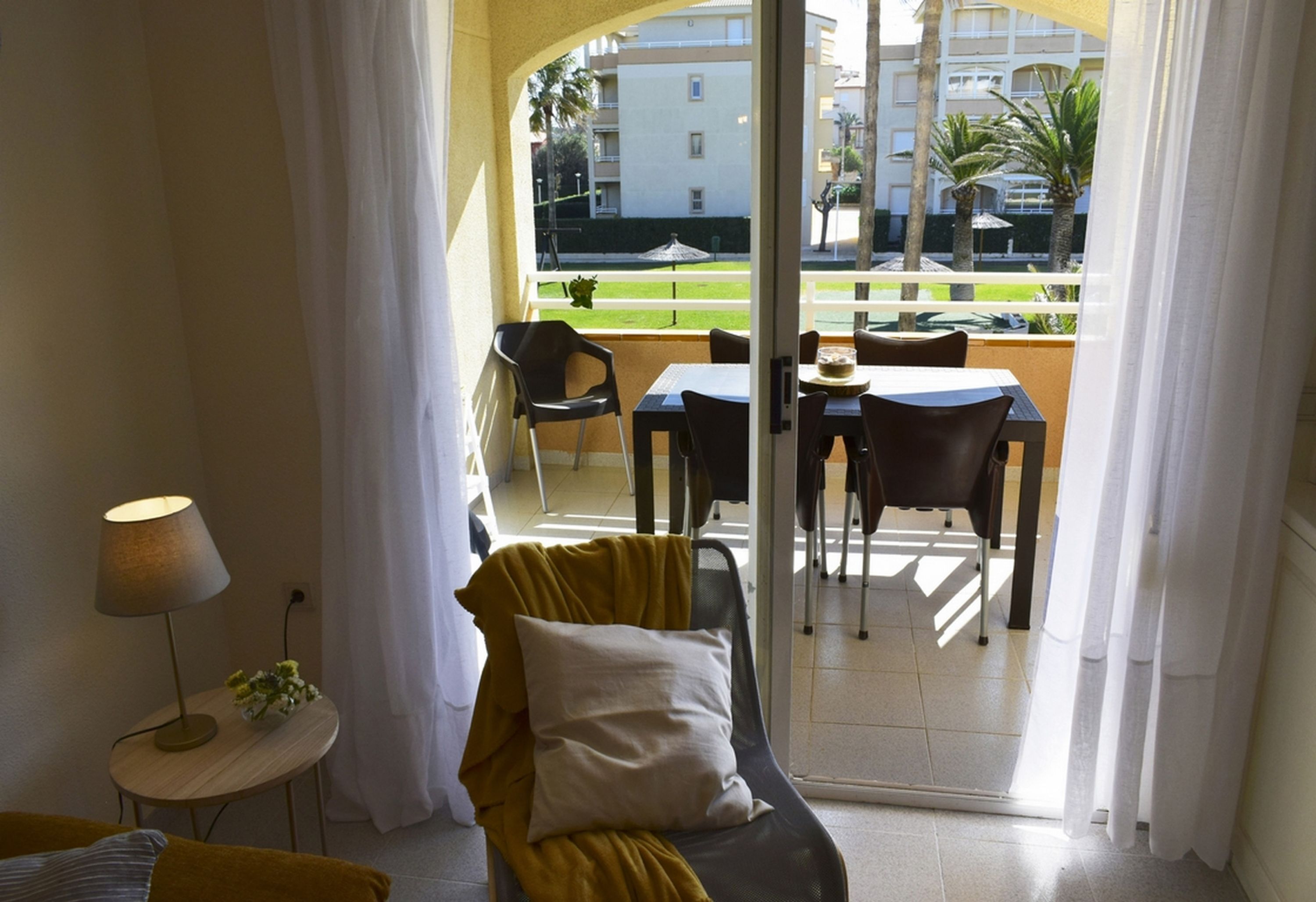 A balcony with a table and chairs, a sofa, and a lamp.