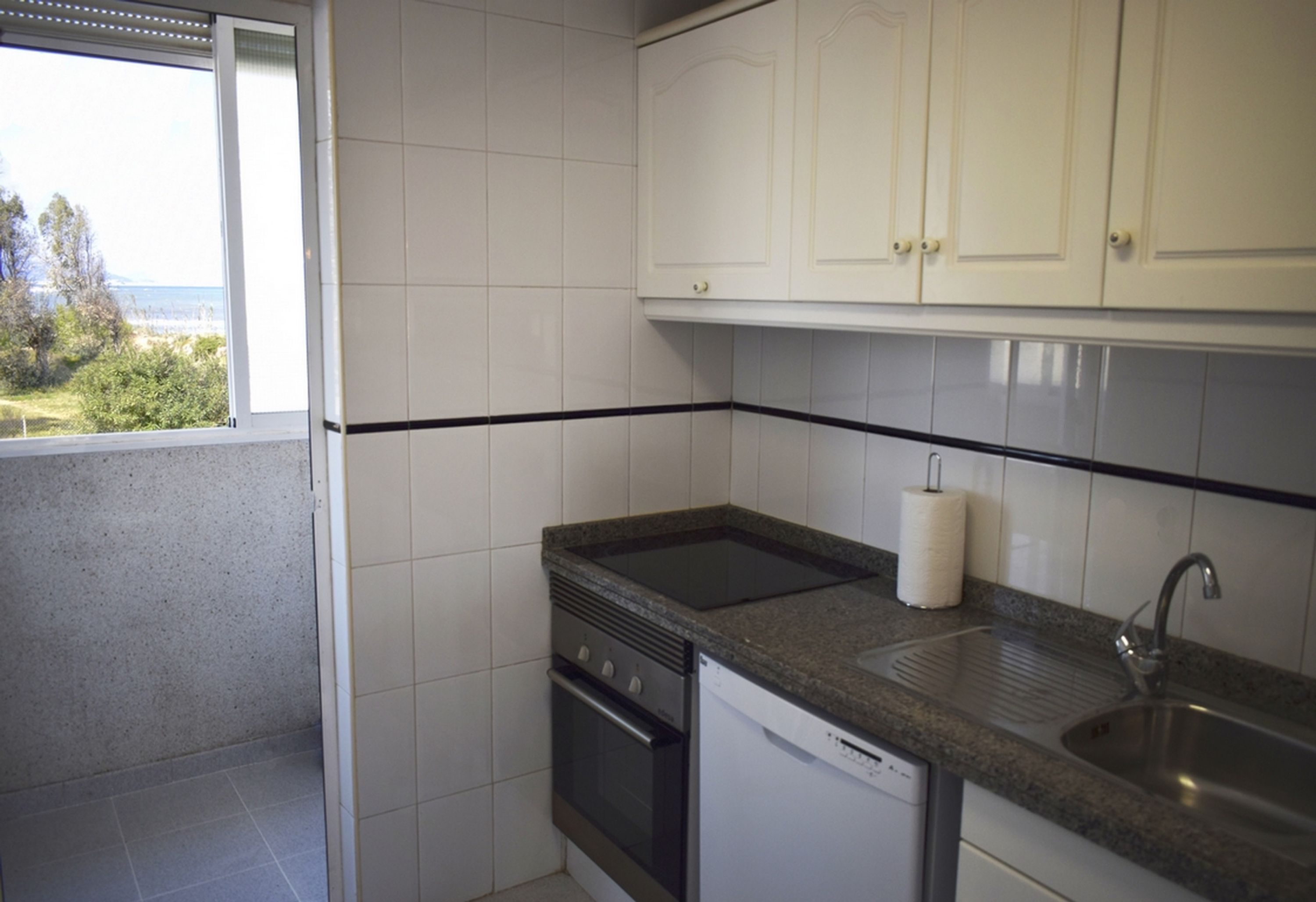 Een keuken met witte kasten, een zwart aanrecht, een fornuis en een vaatwasser.