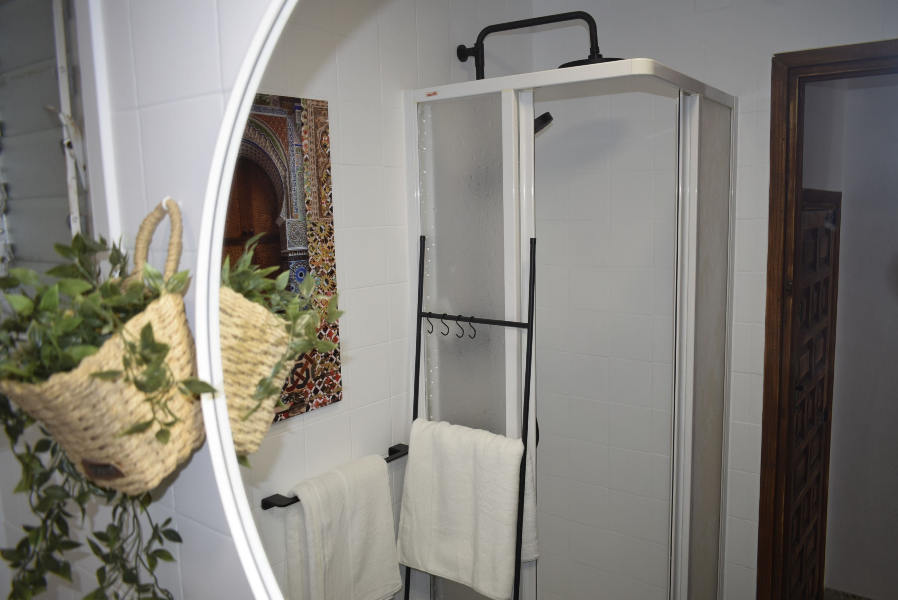 A bathroom with a shower, a towel rack, and a decorative wall tile.