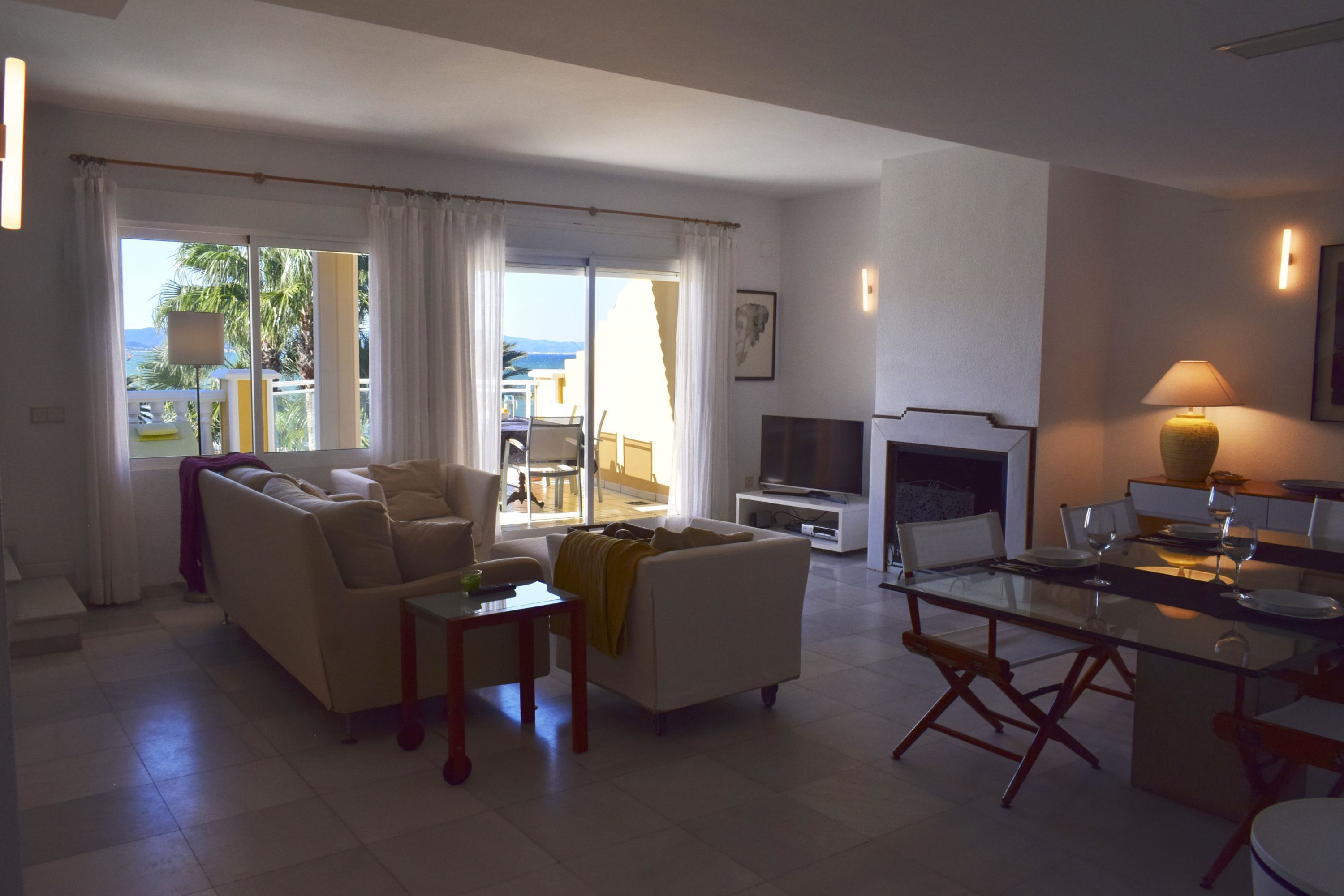 A modern living room with a sofa, coffee table, and dining area with a glass table.