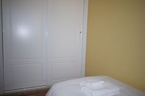 A bedroom with a bed, white towels, a wardrobe, and a yellow wall. - Ap2243 in Denia With 2 Bedrooms and 2 Bathrooms (Denia)