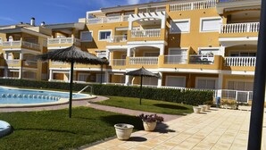 Ein Hotelinnenhof mit Schwimmbad, Topfpflanzen und Sonnenschirmen.