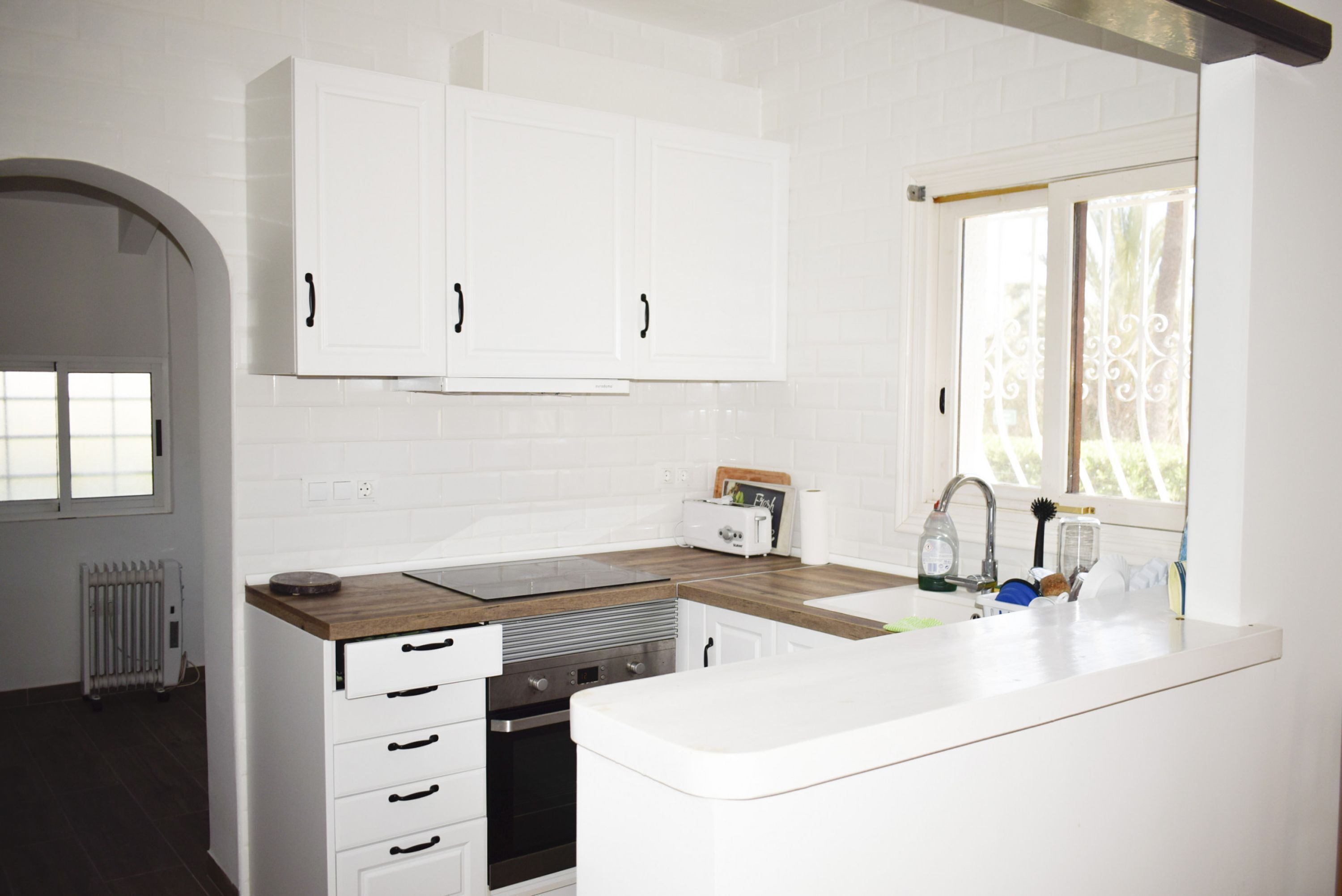 A modern kitchen with white cabinets, a wooden countertop, and a built-in oven.