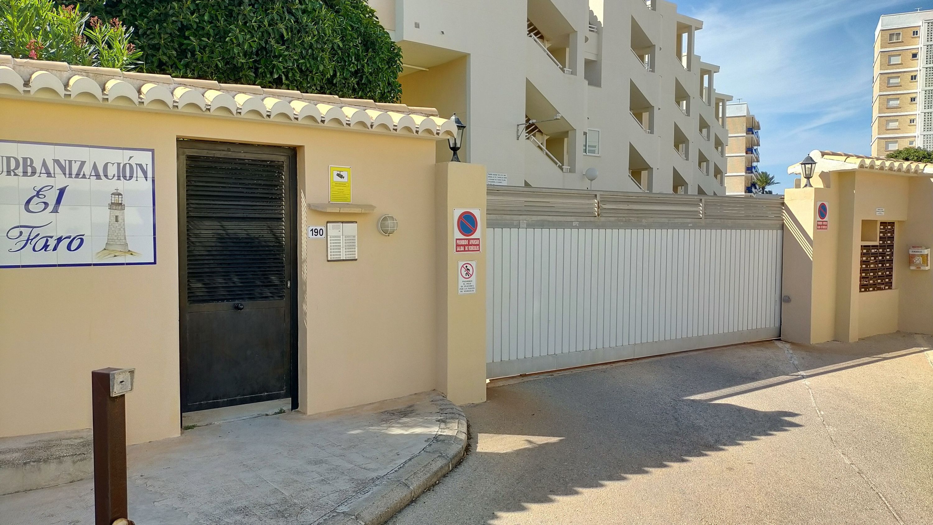 A gated entrance to a residential building with a sign reading "URBANIZACION El Faro".