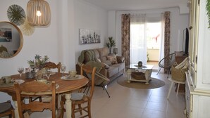 A dining area with a wooden table and chairs, a sofa, and a television in the background. - Ap2236 in Denia With 2 Bedrooms and 2 Bathrooms (Denia)