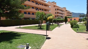 Hotel de varios pisos con un patio central, rodeado de vegetación y un cielo despejado.