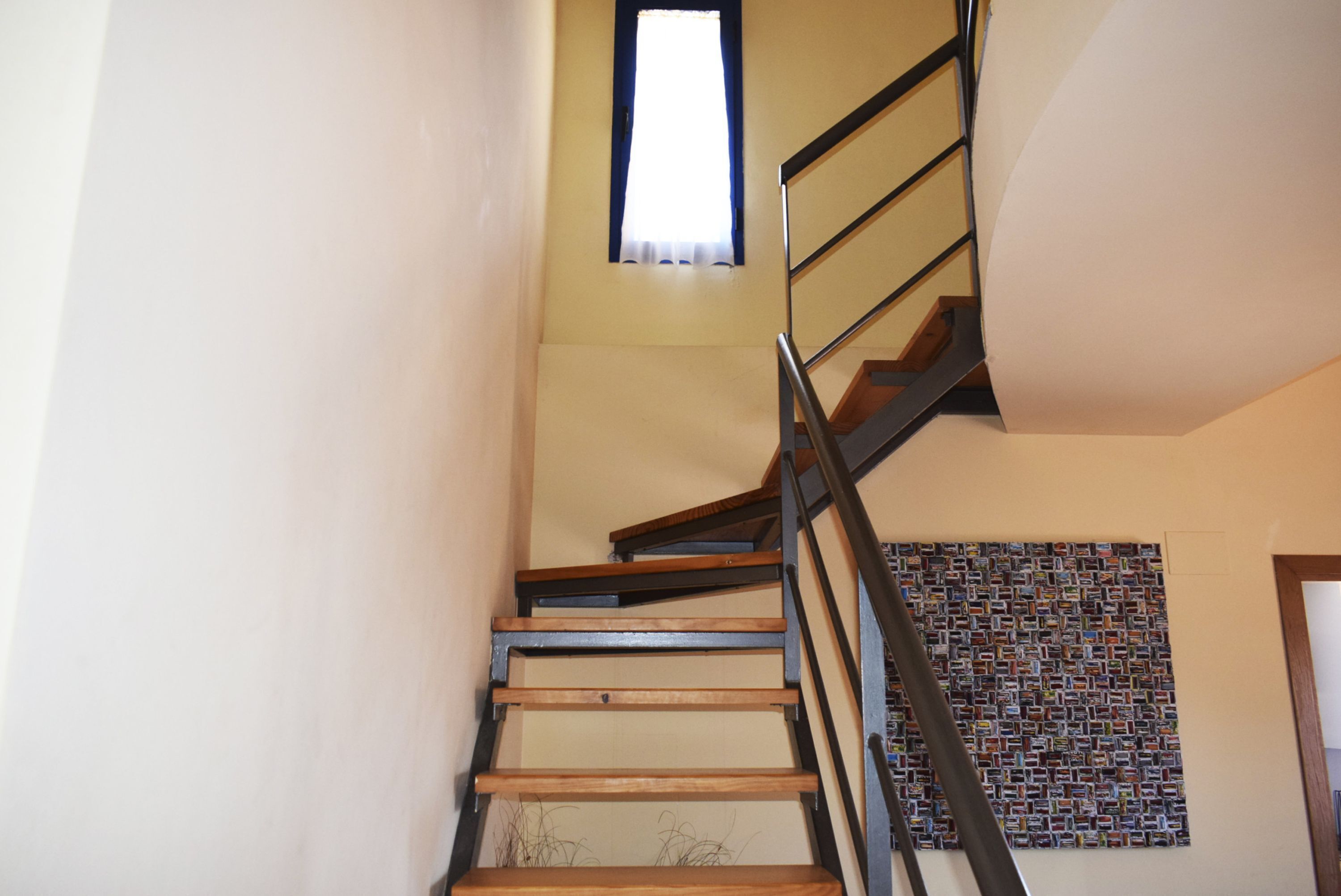 A staircase with wooden steps and black railings, leading to a landing with a patterned wall.