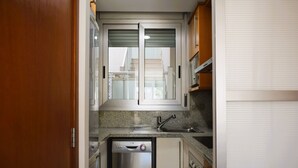 Eine kleine Küche mit Geschirrspüler, Spüle und einem Fenster mit Jalousien.