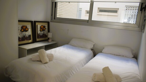 Ein Hotelzimmer mit zwei Einzelbetten, weißer Bettwäsche und einem Bild an der Wand.