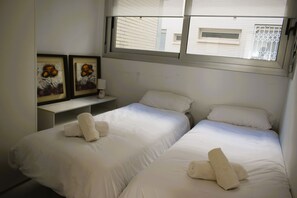 Une chambre d’hôtel avec deux lits simples, du linge de lit blanc et des œuvres d’art accrochées au mur.