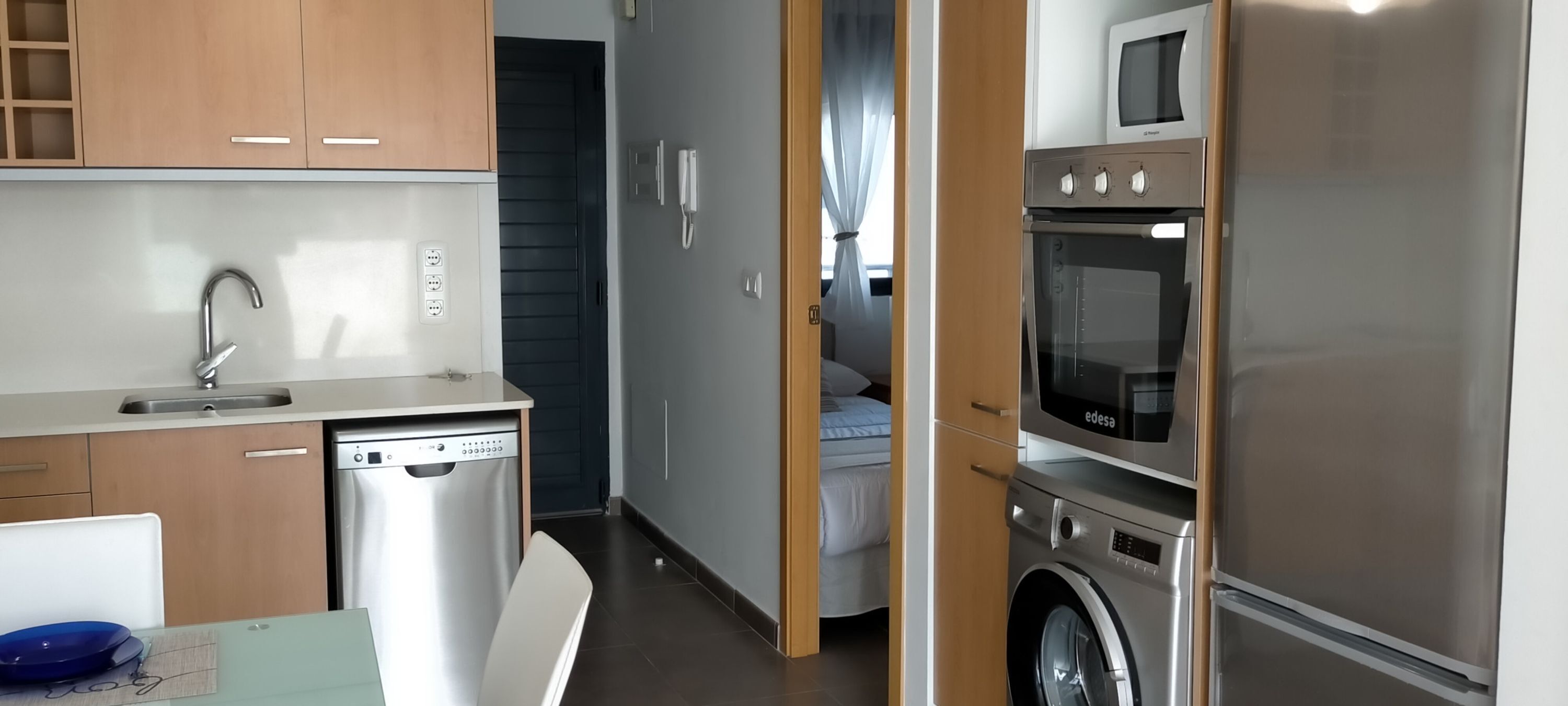 A compact kitchen with a dishwasher, washing machine, and a microwave.