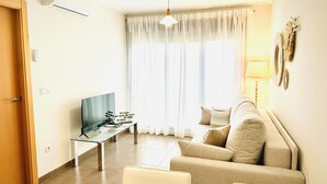 A living room with a sofa, a TV, and a table with decorative items. - Ap313 in Oliva With 2 Bedrooms and 1 Bathrooms (Oliva)