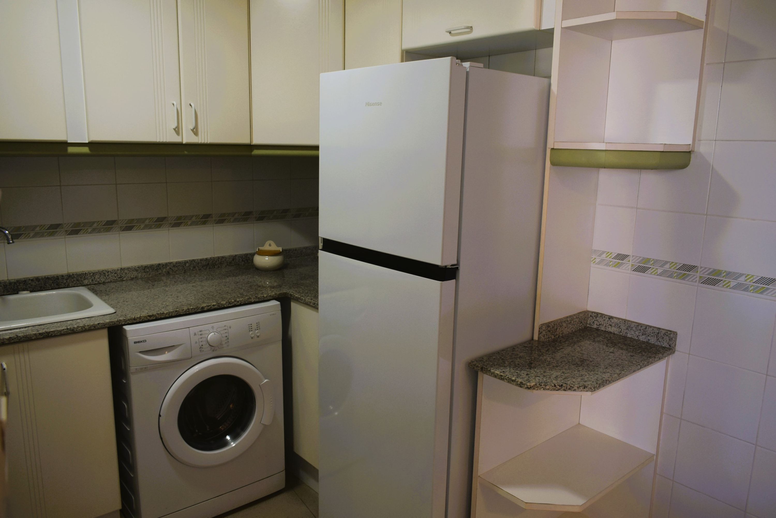Eine Küche mit Waschmaschine, Kühlschrank und Arbeitsplatte.