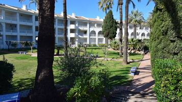 A hotel with multiple balconies, a well-maintained lawn, and a pathway.