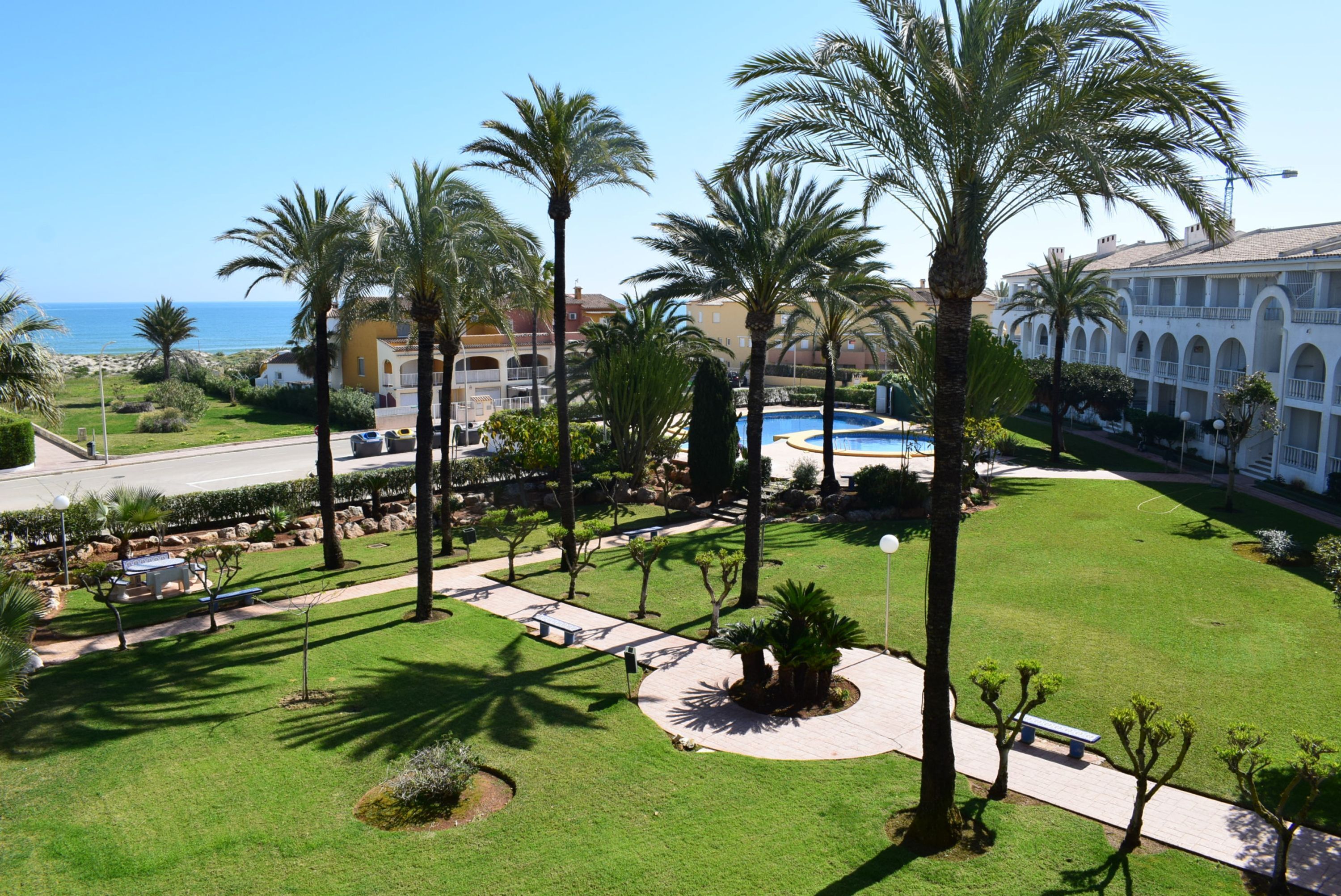 A resort with a pool, palm trees, and a view of the sea.