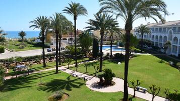 A resort with a pool, palm trees, and a view of the sea.
